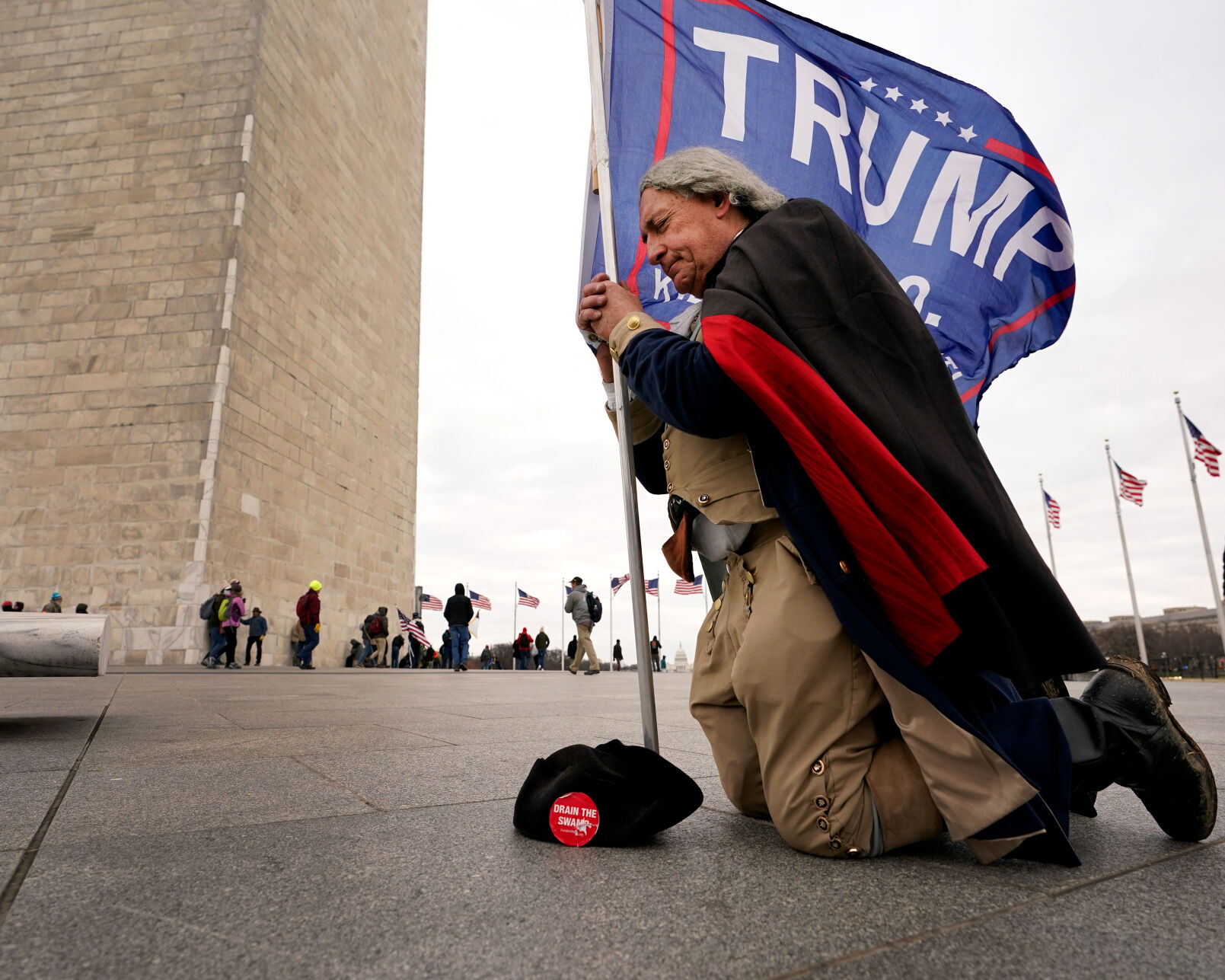A man dressed as George Washington kneels and prays